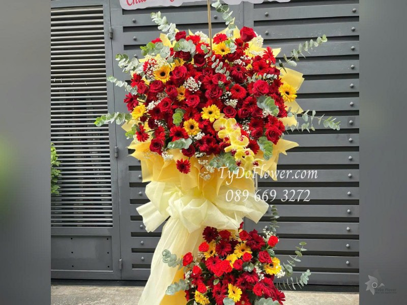 KCM0625448 KỆ HOA CHÚC MỪNG KHAI TRƯƠNG HỒNG PHÁT Thiết kế tông màu đỏ vàng, chủ đạo Hoa Hồng Đỏ Ecuador, Lan Hồ Điệp Vàng, Đồng Tiền Đỏ Vàng