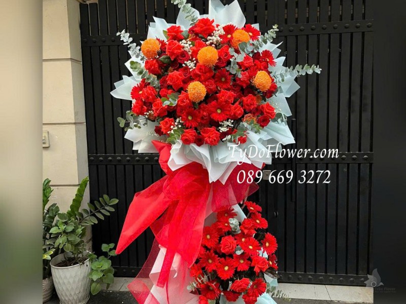 KCM0226178 KỆ HOA 02 TẦNG CHÚC MỪNG KHAI TRƯƠNG Thiết kế tông màu đỏ cam, chủ đạo hoa hồng, đồng tiền, cúc mẫu đơn trên nền giấy mỹ thuật cao cấp