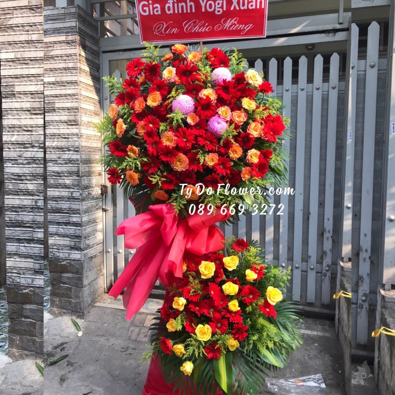 KCM01241261 KỆ HOA CHÚC MỪNG thiết kế tone màu đỏ-cam chủ đạo Hoa Hồng Cam Spirit Roses, Đồng Tiền Đỏ, điểm nhấn Cúc Mẫu Đơn Hồng