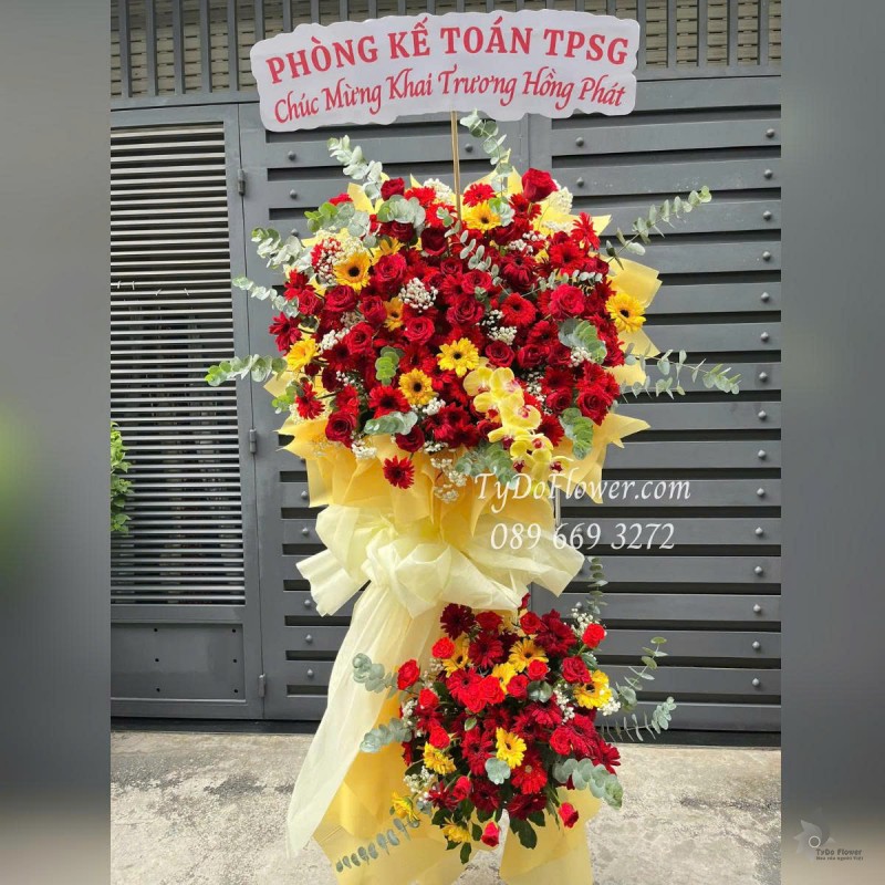 KCM0625448 KỆ HOA CHÚC MỪNG KHAI TRƯƠNG HỒNG PHÁT Thiết kế tông màu đỏ vàng, chủ đạo Hoa Hồng Đỏ Ecuador, Lan Hồ Điệp Vàng, Đồng Tiền Đỏ Vàng