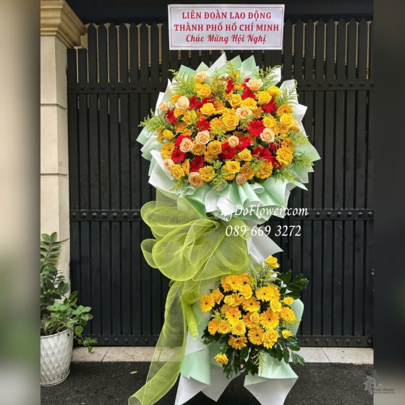 KCM1025853 KỆ HOA CHÚC MỪNG HỘI NGHỊ Thiết kế hoa hồng vàng cam, đồng tiền đỏ vàng trên nền giấy mỹ thuật cao cấp