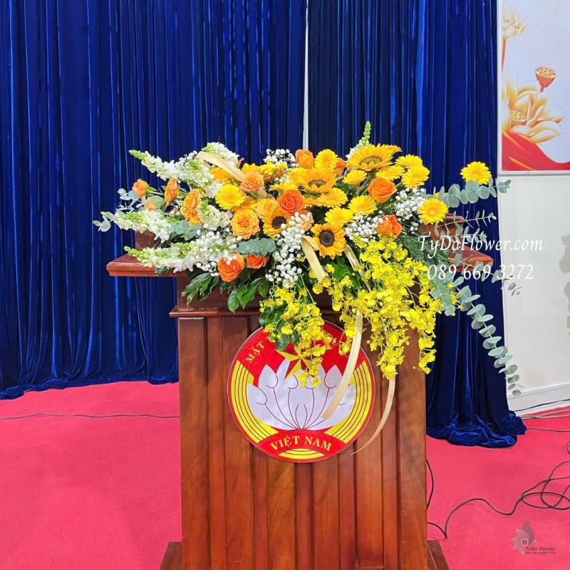 L1025861 HOA TRANG TRÍ BỤC PHÁT BIỂU Thiết kế Hoa hồng cam Spirit, hướng dương, đồng tiền, lan vũ nữ