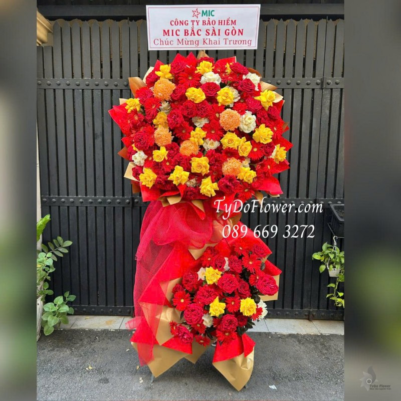 KCM0226120 KỆ HOA 02 TẦNG CHÚC MỪNG KHAI TRƯƠNG Thiết kế tông màu đỏ vàng cam, chủ đạo hoa hồng, đồng tiền, cúc mẫu đơn