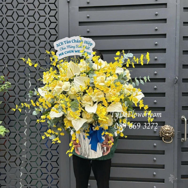 G0226162 GIỎ HOA CHÚC MỪNG SINH NHẬT Thiết kế tông màu vàng, hoa lan vũ nữ, lá môn trắng, hoa hồng vàng victor